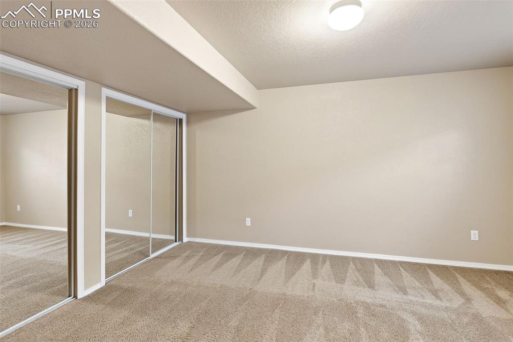 Image 29 of 44: Bedroom in basement with mirrored closet doors.