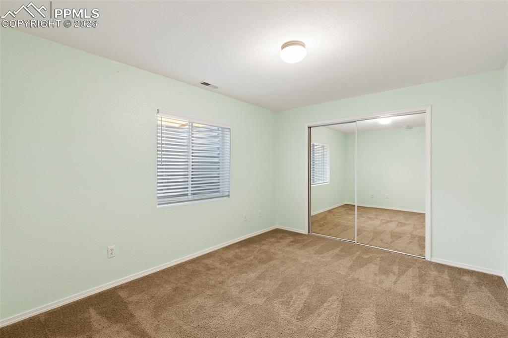 Image 31 of 44: Bedroom in basement with mirrored closet door.