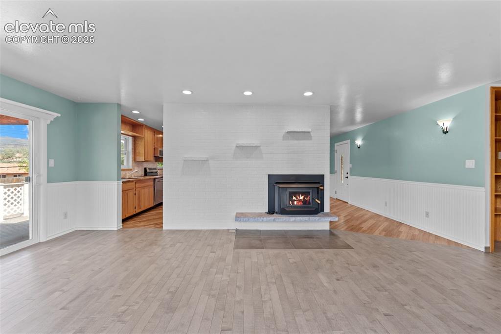 Image 10 of 34: Open-concept living space featuring light wood-finish flooring, a white bri