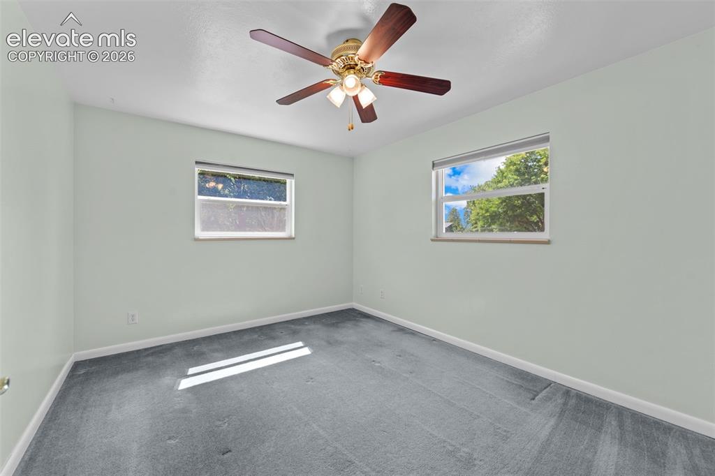 Image 17 of 34: Room with light-toned walls, grey carpeting, a ceiling fan with integrated 