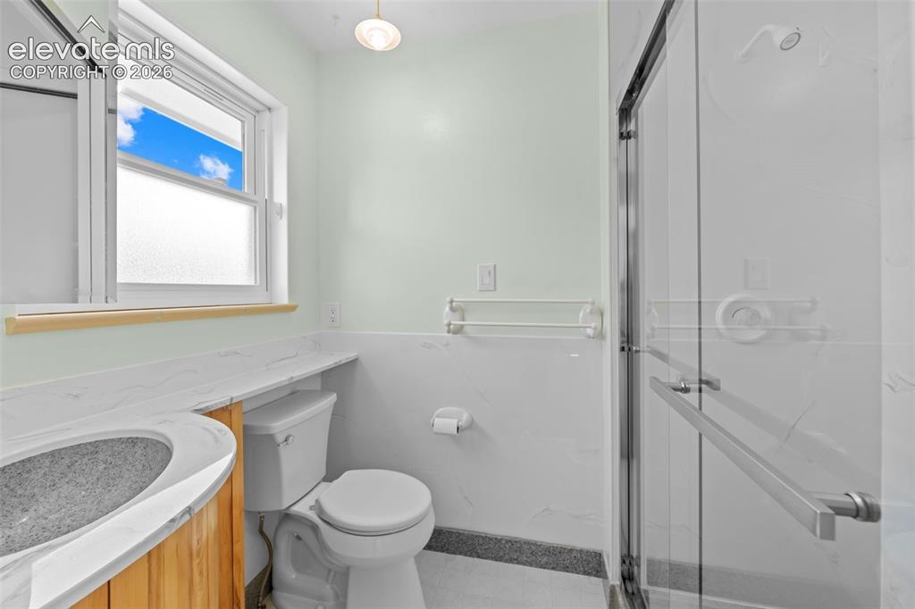 Image 19 of 34: Bathroom featuring a glass-enclosed shower, a vanity with a dark basin and 