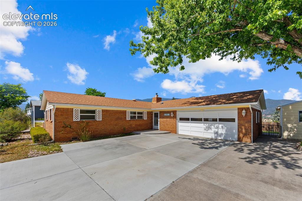 Image 2 of 34: Brick exterior home featuring a two-car garage, concrete driveway, and whit