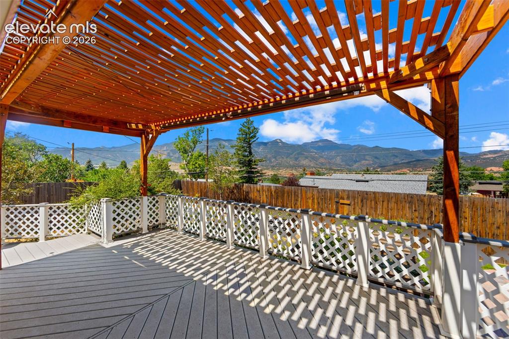Image 25 of 34: Expansive outdoor deck featuring a slat-style pergola, composite decking, w