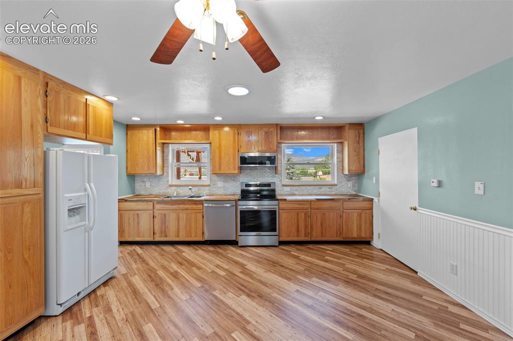 Image 6 of 34: Kitchen featuring wood-finish flooring, natural wood cabinetry, a tile back