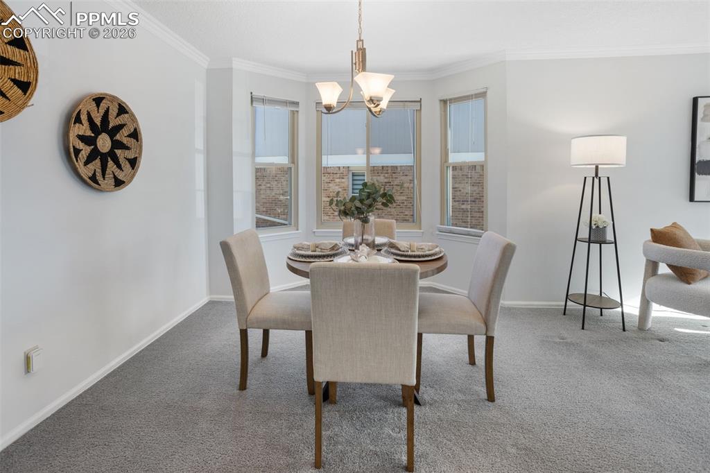 Image 12 of 31: Carpeted dining room featuring ornamental molding and a chandelier