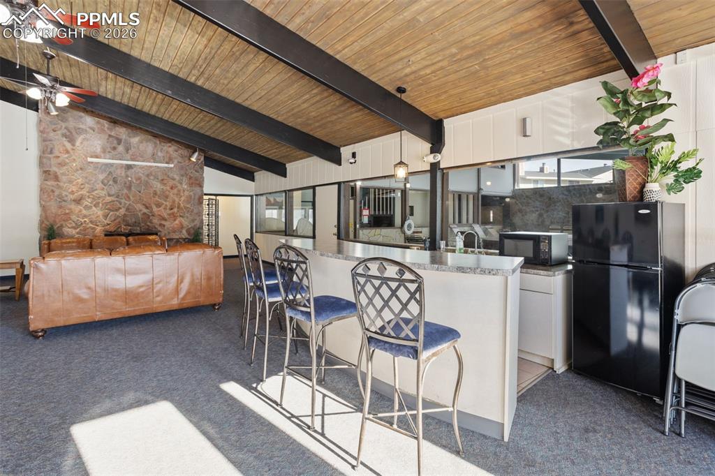 Image 31 of 31: COMMUNITY CLUBHOUSE: Kitchen with white cabinetry, black appliances, a brea
