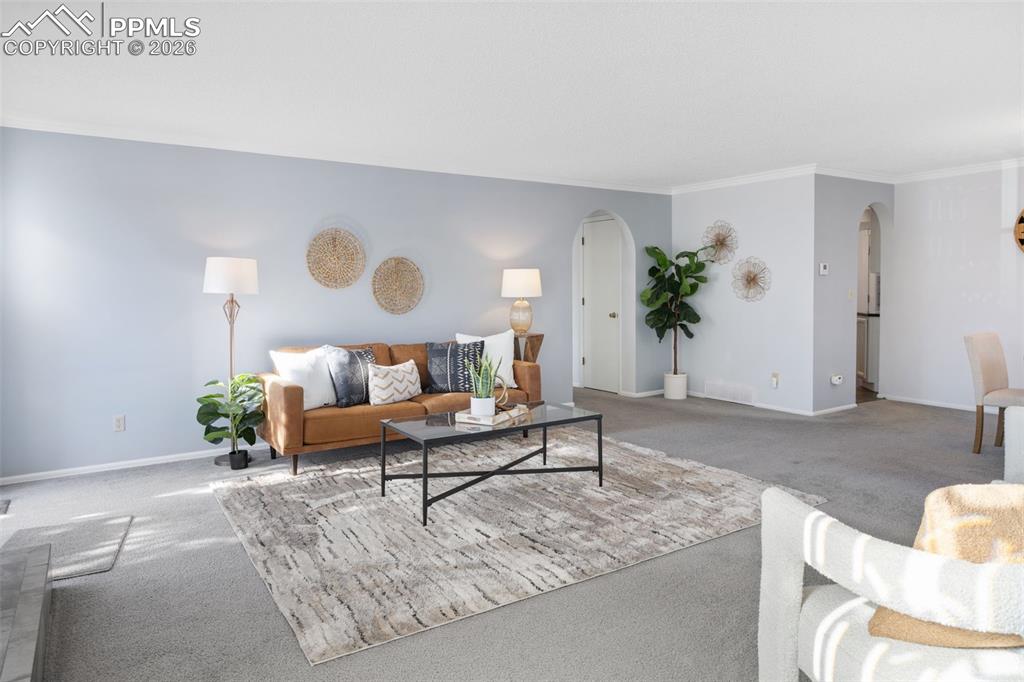 Image 5 of 31: Carpeted living room with arched walkways and ornamental molding