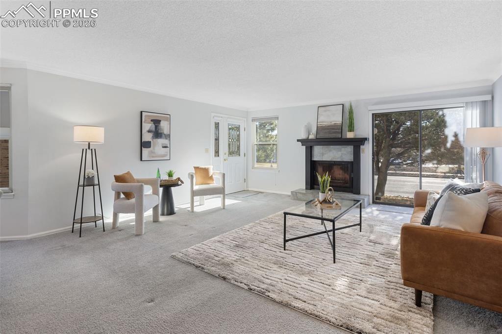 Image 8 of 31: Living area featuring a tiled fireplace, carpet floors, and a textured ceil