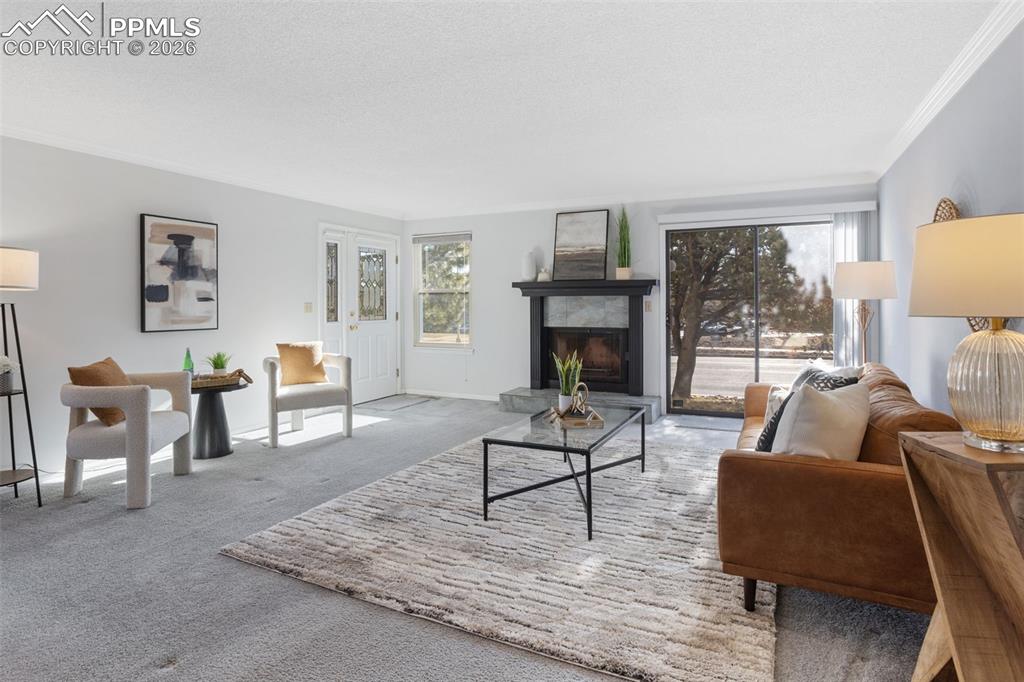 Image 9 of 31: Carpeted living room featuring a tiled fireplace, a textured ceiling, and o