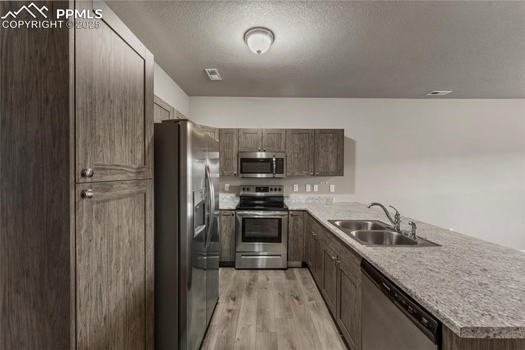 Image 11 of 29: Kitchen with appliances with stainless steel finishes, a peninsula, a textu