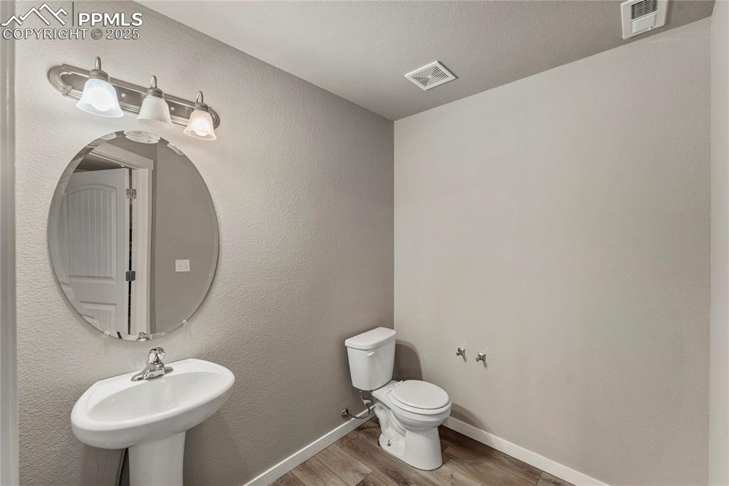 Image 14 of 29: Half bath featuring wood finished floors and a textured wall