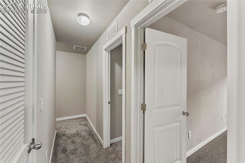 Image 22 of 29: Hall with carpet and a textured ceiling