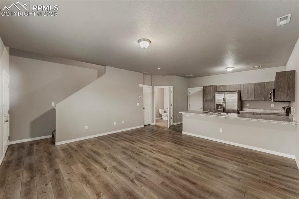 Image 5 of 29: Unfurnished living room with dark wood-style flooring and a textured ceilin