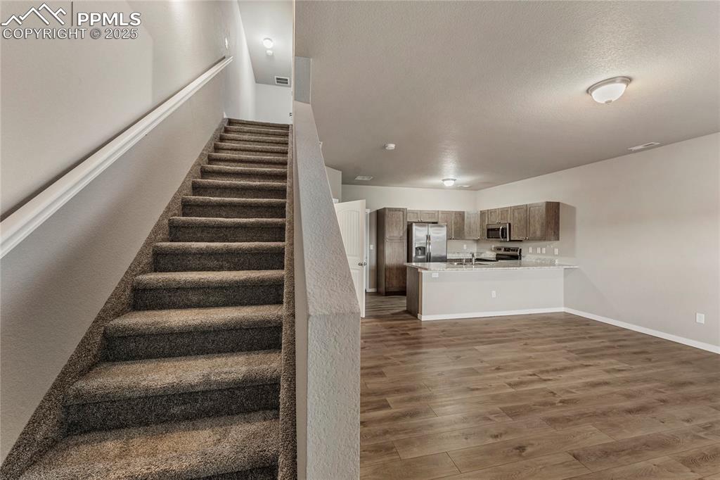 Image 6 of 29: Stairway with wood finished floors and a textured ceiling