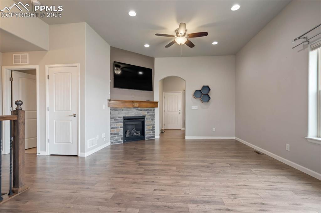 Image 10 of 45: Unfurnished living room featuring ceiling fan, arched walkways, wood finish