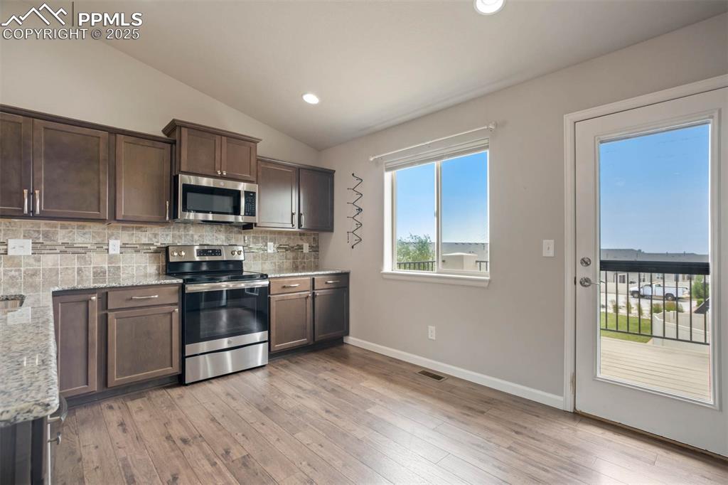 Image 12 of 45: Kitchen featuring appliances with stainless steel finishes, backsplash, vau