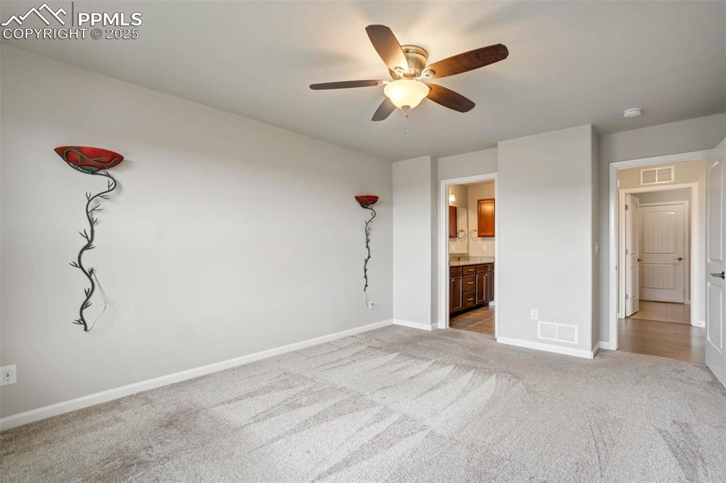 Image 18 of 45: Unfurnished bedroom with light carpet, ensuite bath, and a ceiling fan
