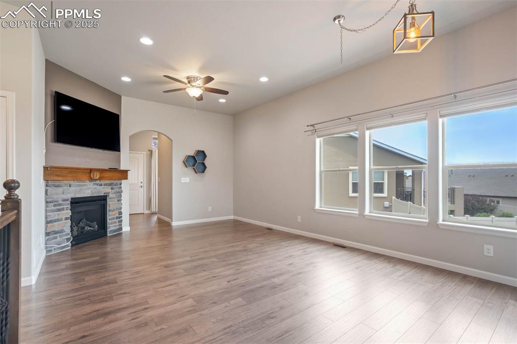 Image 2 of 45: Unfurnished living room with a ceiling fan, arched walkways, wood finished 