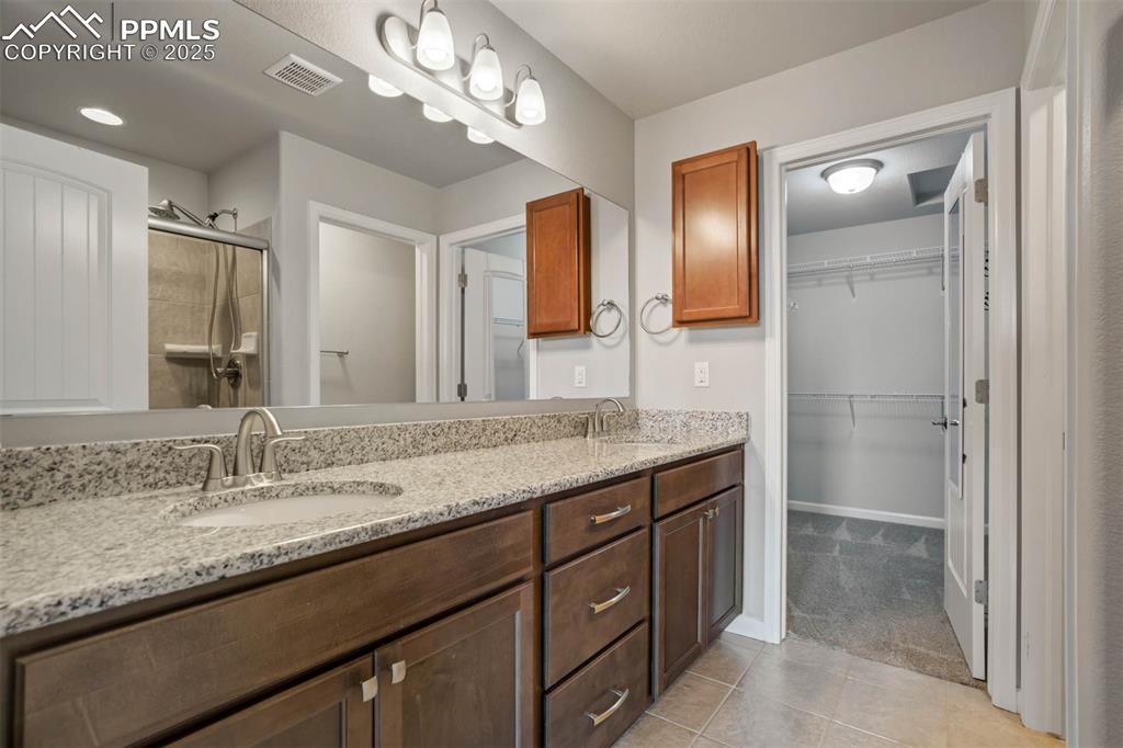Image 21 of 45: Full bathroom with a stall shower, double vanity, tile patterned floors, an