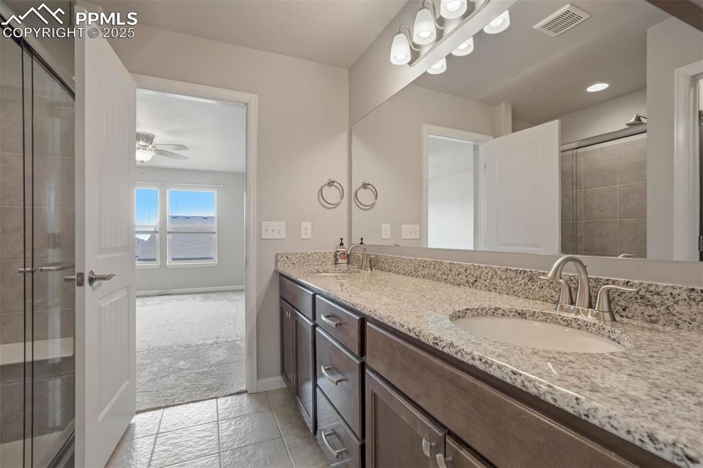 Image 22 of 45: Bathroom with double vanity, tile patterned floors, a tile shower, ceiling 