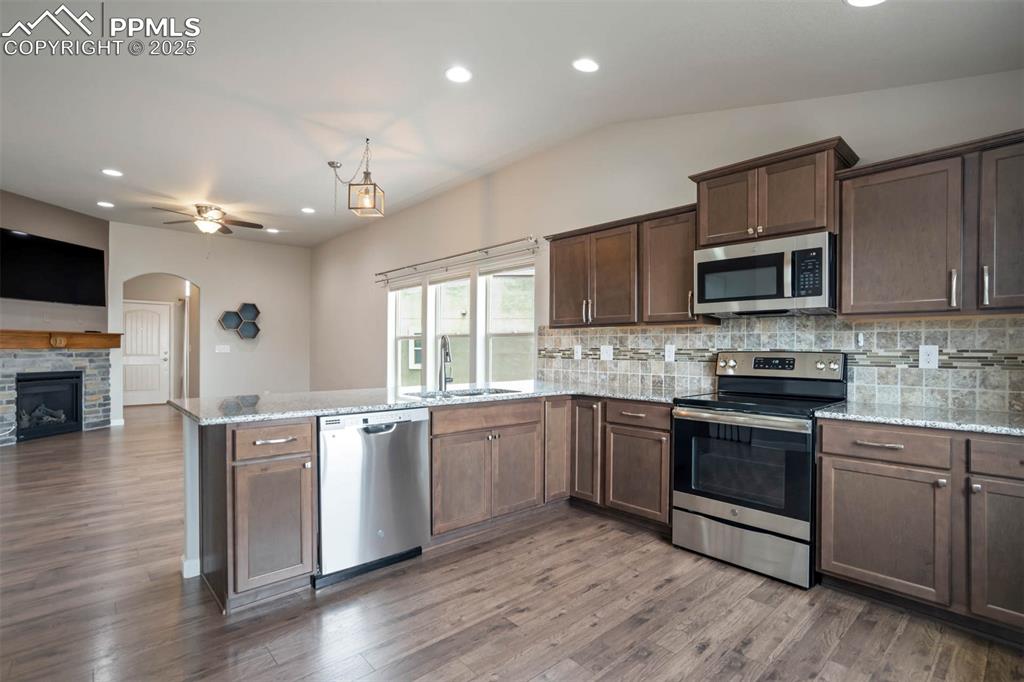 Image 3 of 45: Kitchen featuring appliances with stainless steel finishes, a peninsula, ba