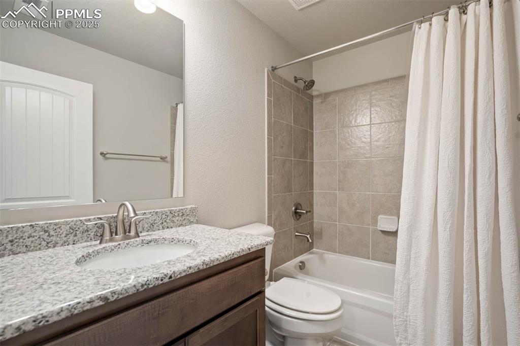 Image 38 of 45: Bathroom featuring shower / bathtub combination with curtain, vanity, and a