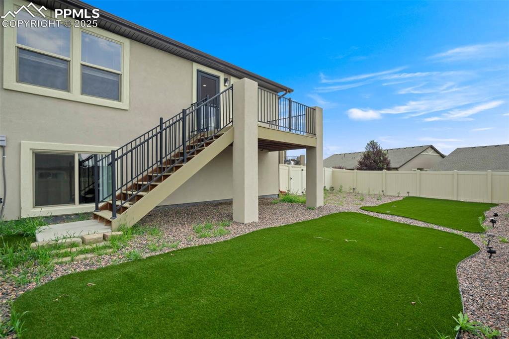Image 4 of 45: Back of house featuring stucco siding, stairs, a fenced backyard, a deck, a
