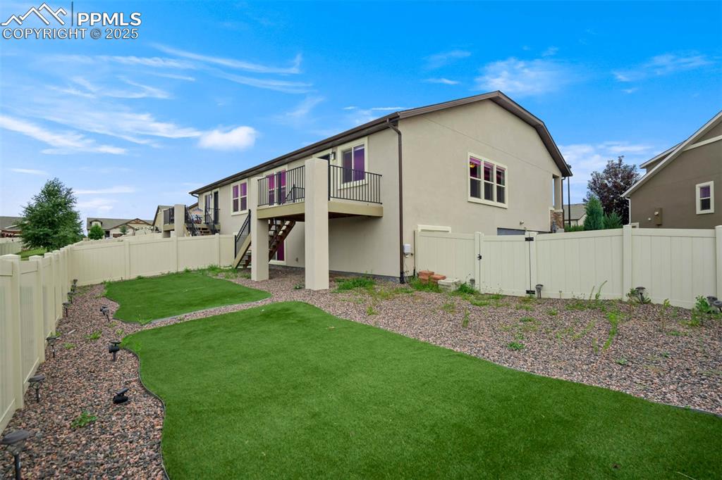 Image 42 of 45: Rear view of house with a fenced backyard, stairway, stucco siding, and a d