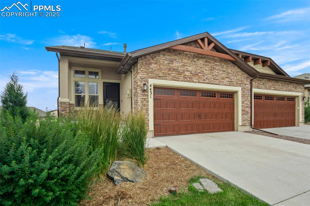 Image 44 of 45: Craftsman-style house with a garage, concrete driveway, stone siding, and s