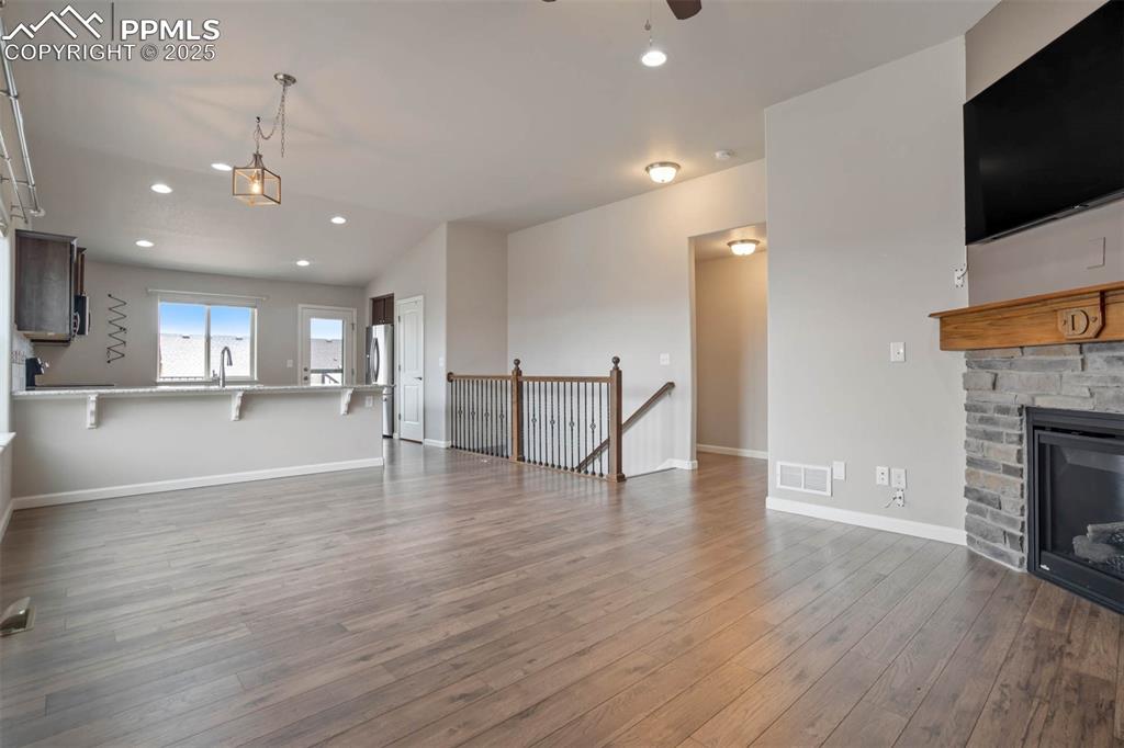 Image 8 of 45: Unfurnished living room with wood finished floors, a ceiling fan, recessed 