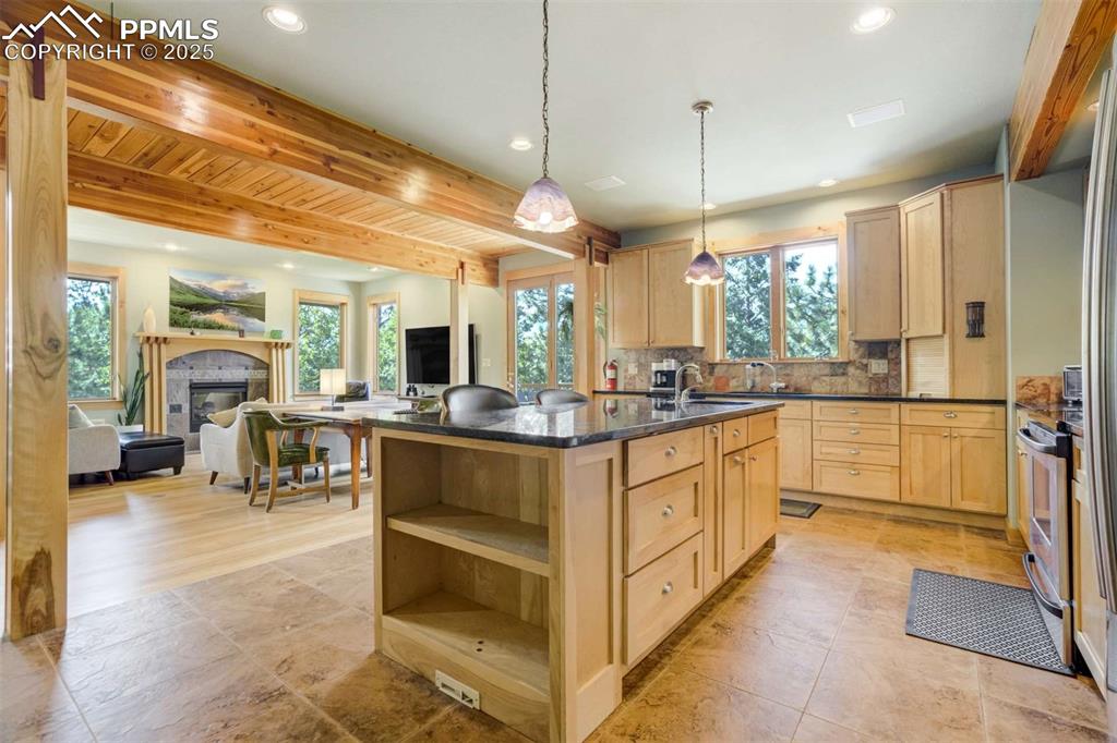 Image 16 of 50: Kitchen with light birch cabinetry, beamed ceiling, open floor plan, granit