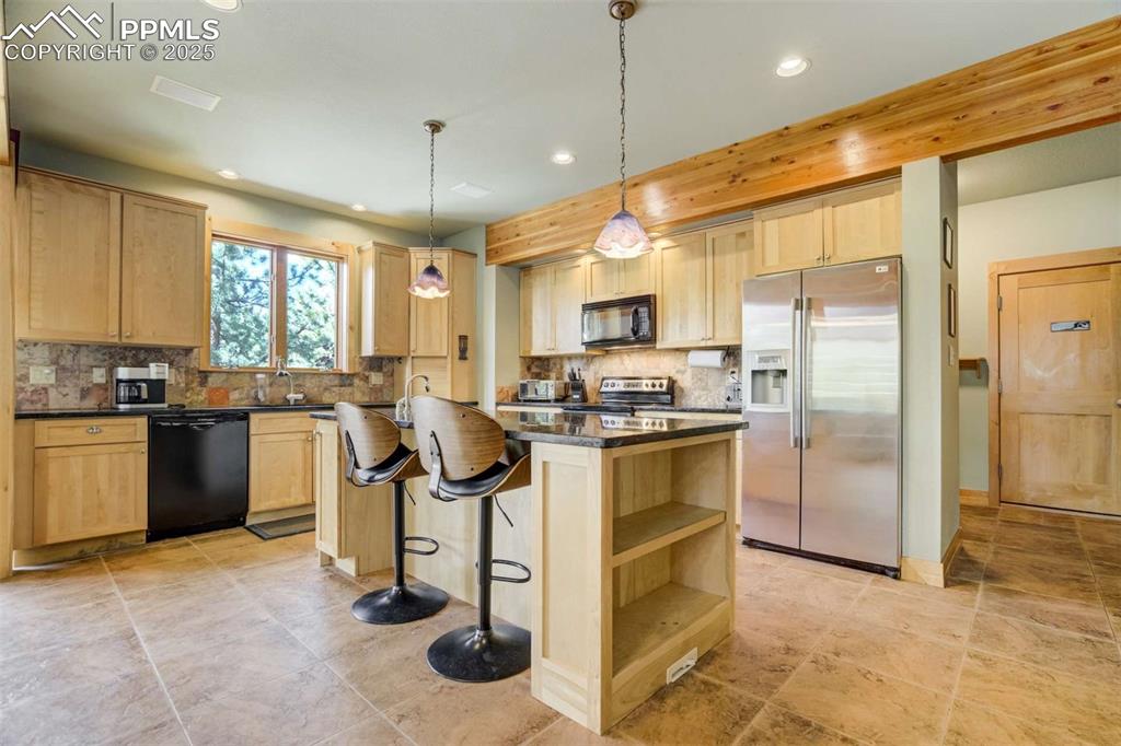 Image 17 of 50: Kitchen featuring black appliances, a kitchen island, a breakfast bar, and