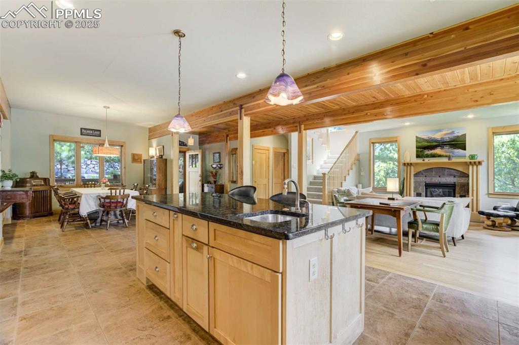 Image 19 of 50: Kitchen featuring a center island with sink, open floor plan, dark granite