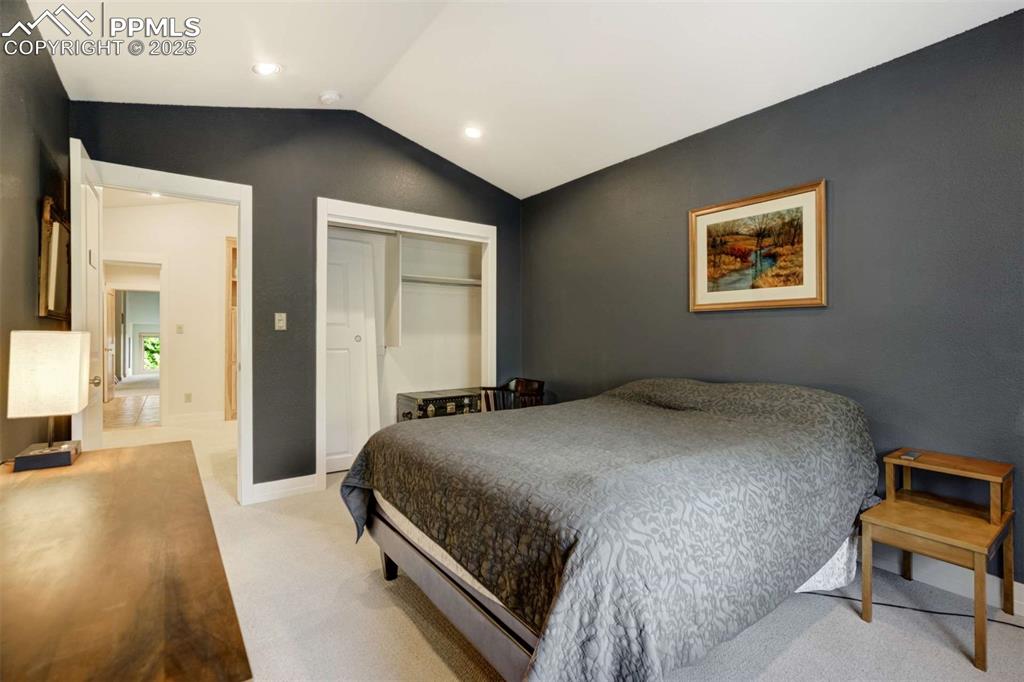 Image 27 of 50: Bedroom with vaulted ceiling, a closet, light colored carpet, and recessed