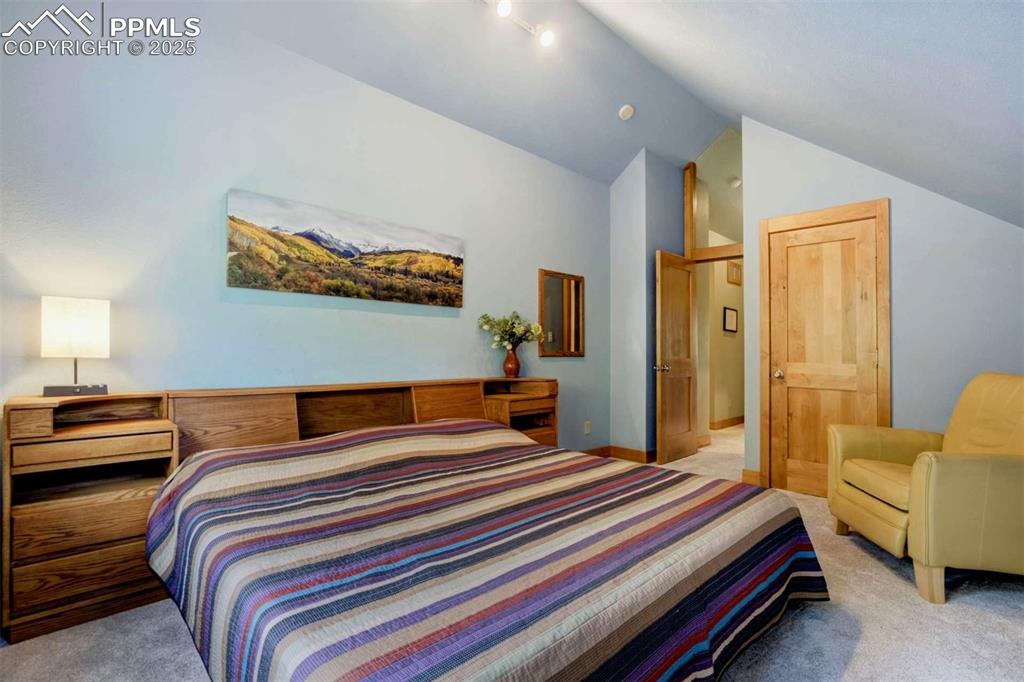 Image 28 of 50: Carpeted bedroom with vaulted ceiling and baseboards
