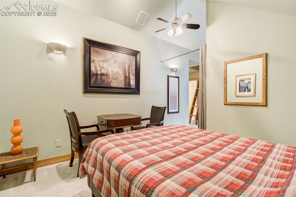 Image 29 of 50: Bedroom with vaulted ceiling, light carpet, and ceiling fan