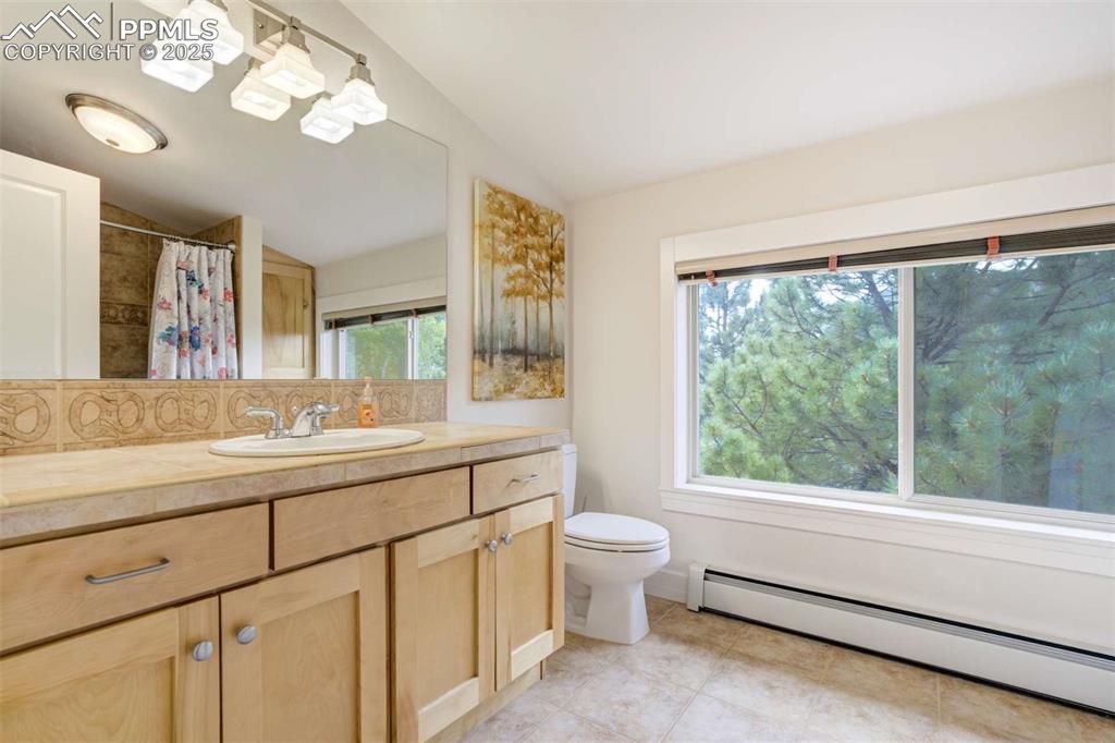 Image 31 of 50: 2nd guest bathroom featuring a baseboard radiator, lofted ceiling, vanity,