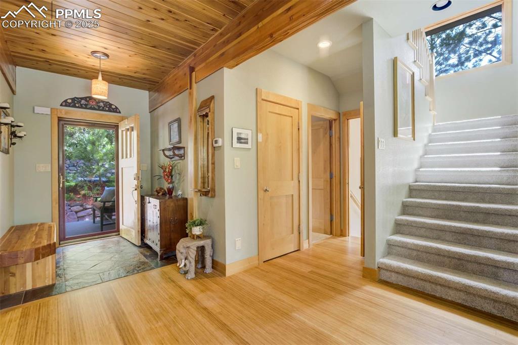 Image 9 of 50: Foyer entrance featuring stairs, bamboo floors, and wood ceiling