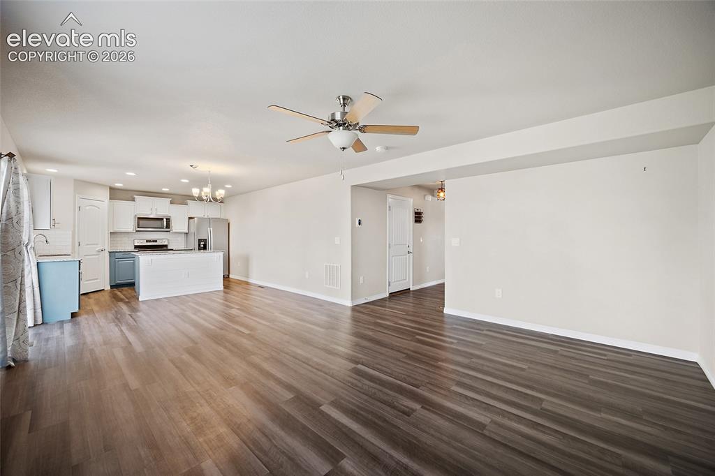Image 10 of 49: Spacious open-concept living area featuring wood-finish flooring, recessed