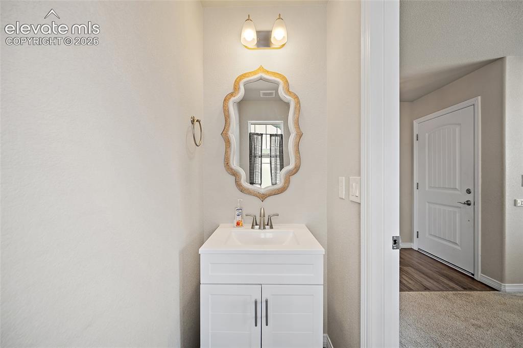 Image 16 of 49: White vanity with a rectangular basin sink, brushed nickel faucet, and deco