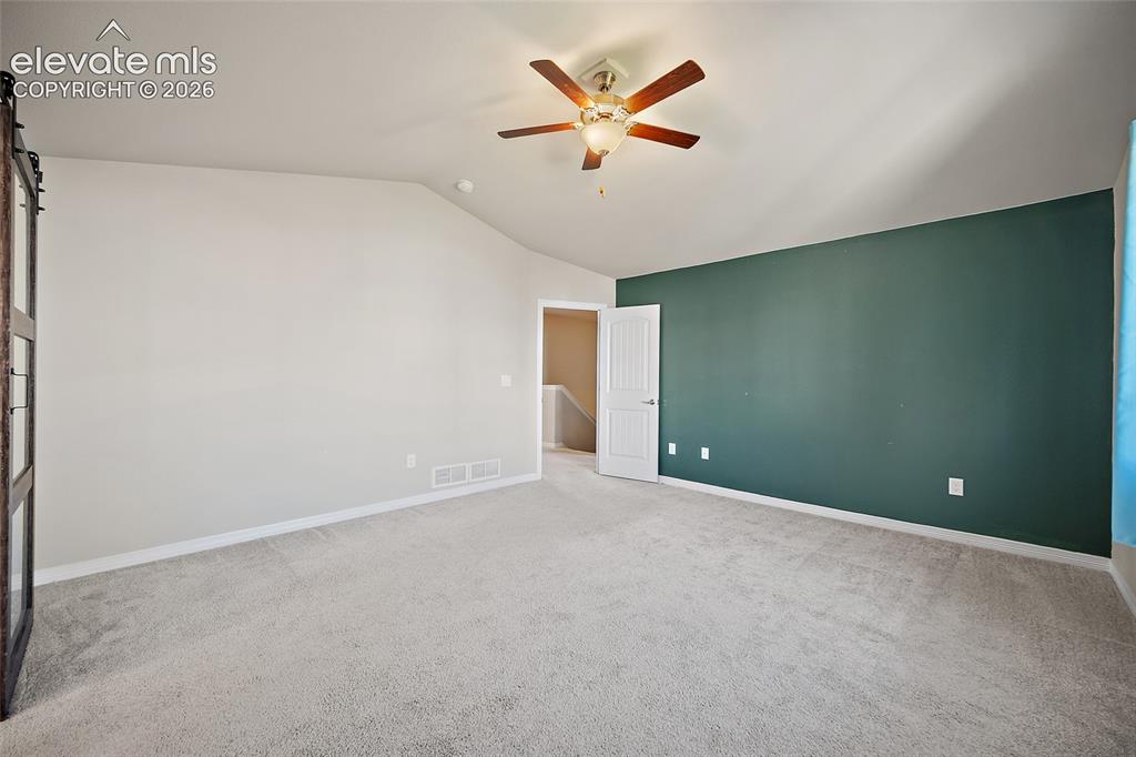 Image 19 of 49: Vaulted ceiling with a ceiling fan, carpeted flooring, and a paneled interi