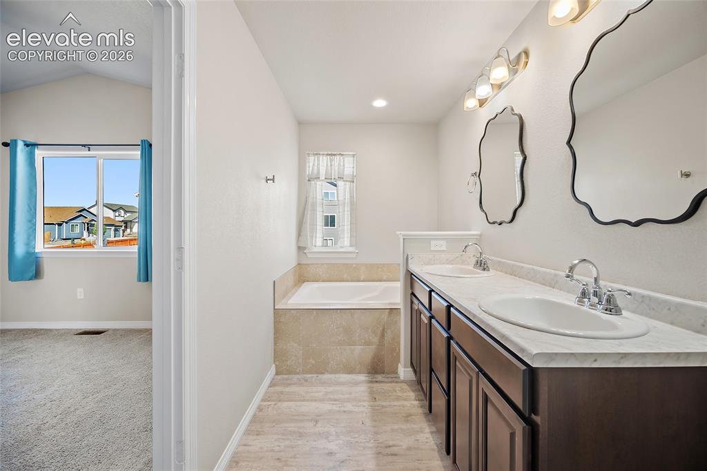 Image 20 of 49: Dual vanity with undermount sinks, built-in soaking tub, wood-finish floori