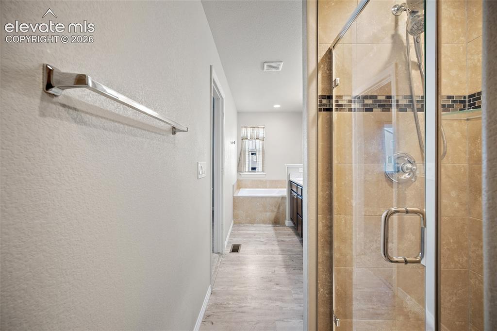 Image 22 of 49: Glass-enclosed shower with tile surround and decorative mosaic accent