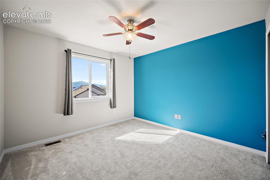 Image 25 of 49: Plush carpeting, a ceiling fan with light fixture, and a window with mounta