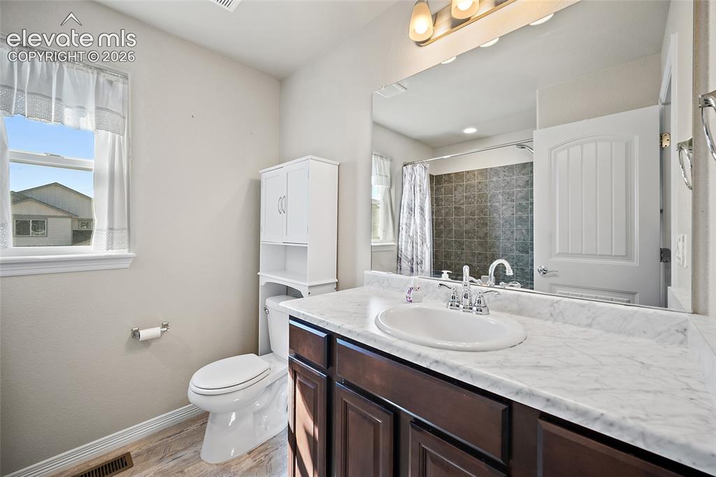 Image 30 of 49: Single vanity with a white countertop and dark wood-finish cabinetry, featu
