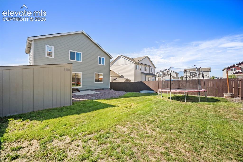 Image 39 of 49: Spacious backyard featuring a storage shed, concrete patio, and privacy fen