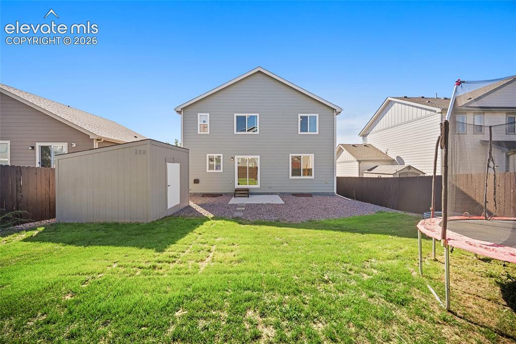 Image 4 of 49: Expansive backyard with a manicured lawn, gravel perimeter, and an outdoor 
