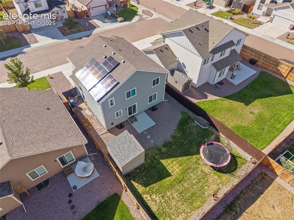 Image 42 of 49: Two-story residential architecture with solar panels, a fenced backyard, an