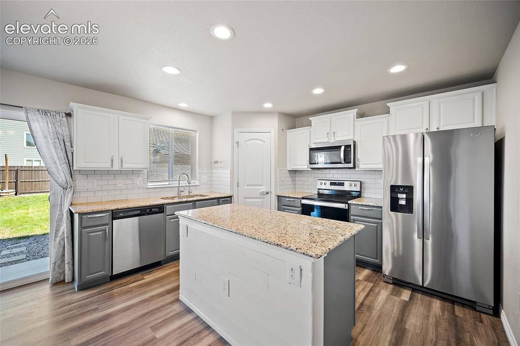 Image 8 of 49: Kitchen featuring wood-finish flooring, two-tone cabinetry, stainless steel