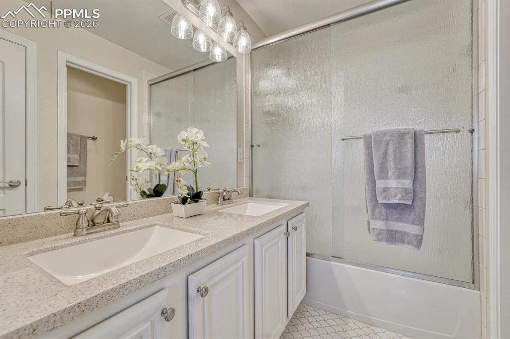 Image 21 of 50: Full primary bathroom has double vanity, granite counter, and decorative ti